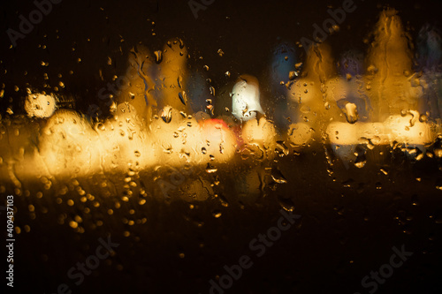 View of the night city through the wet car window with drops