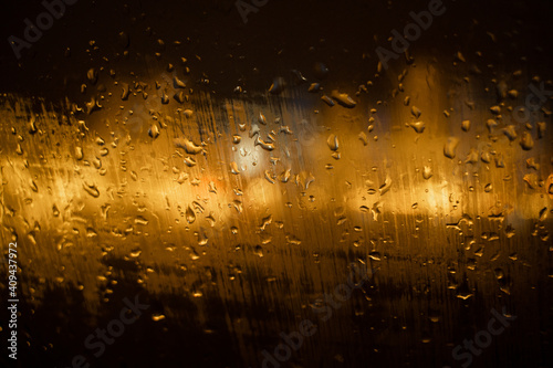 View of the night city through the wet car window with drops