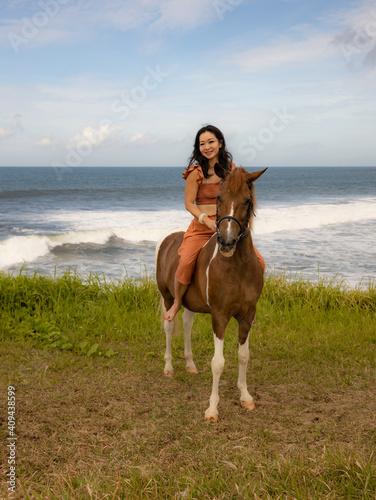 Beautiful woman riding horse near the ocean. Outdoor activities. Human and animals relationship. Traveling concept.