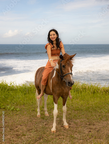 Beautiful woman riding horse near the ocean. Outdoor activities. Human and animals relationship. Traveling concept. Bali