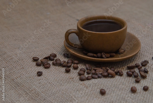 Black coffee in a brown cup and saucer on a burlap background