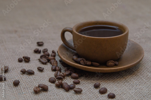 Black coffee in a brown cup and saucer on a burlap background