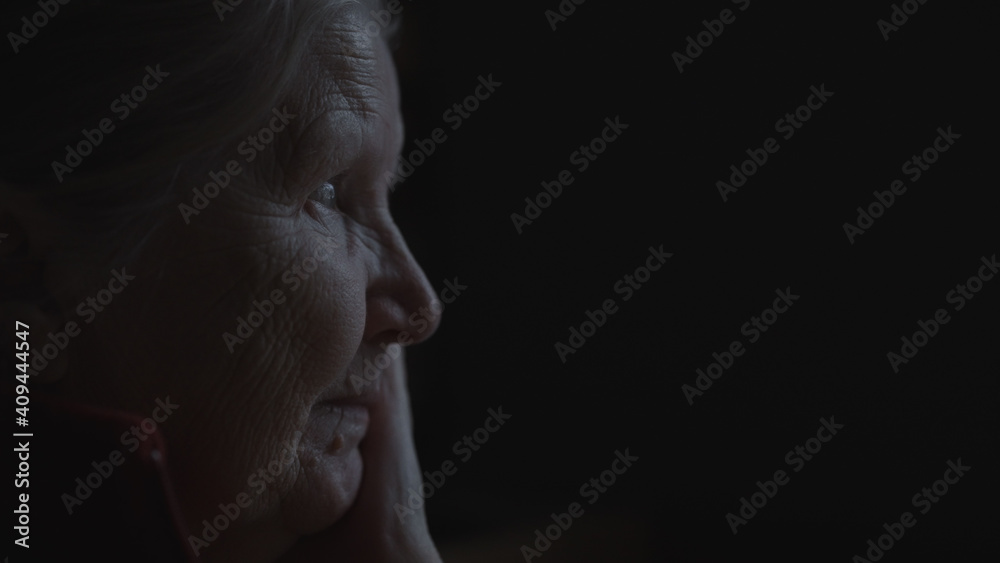shot of old woman sitting near window dark lit