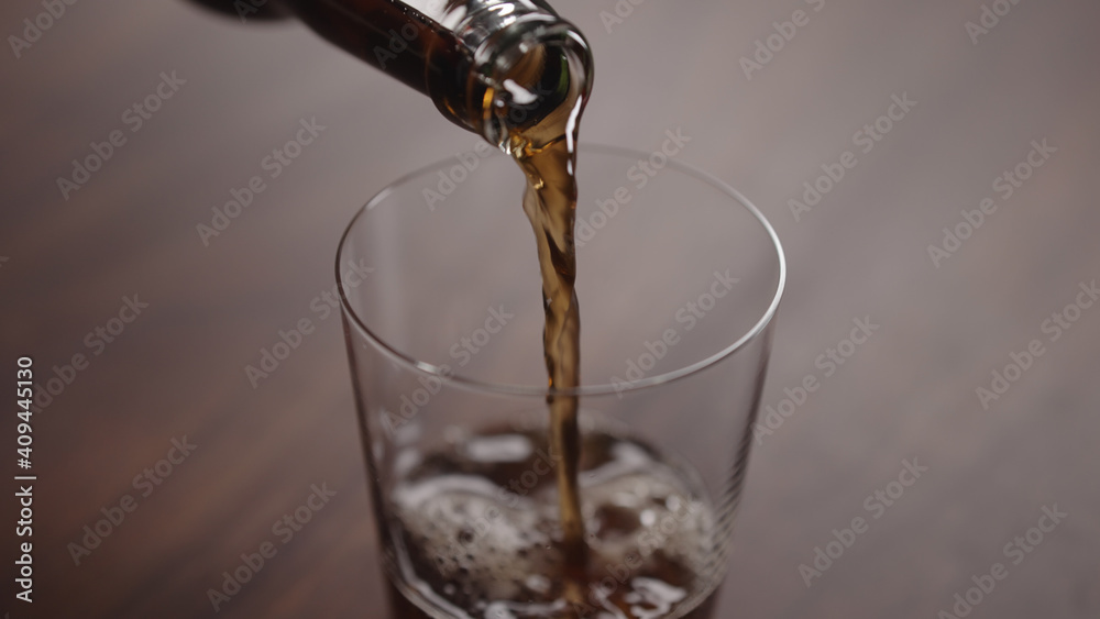 pour cola into tumbler glass on walnut table with copy space