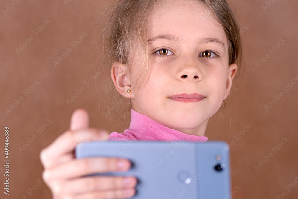 Portrait of a cheerful little girl taking a selfie on brown background Portrait of a cheerful little girl taking a selfie on brown background