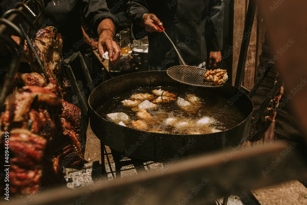 Fototapeta premium chef frying Argentinean food with beef in the background.
