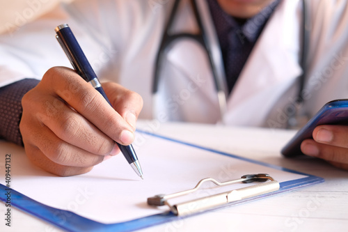 doctor hand writing prescription on desk, close up.