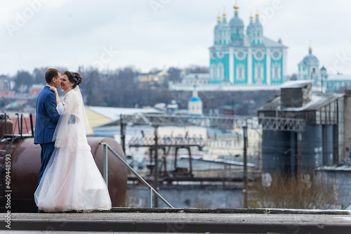 the bride and groom on the background of a church, religious lovers, a wedding walk in winter, a man and a woman gently kiss and smile hugs