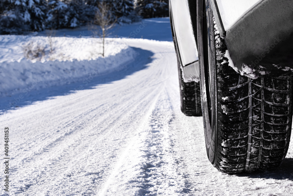 Closeup of car in winter landscape. Road covered with snow. Car tires on snowy road. Winter concept.