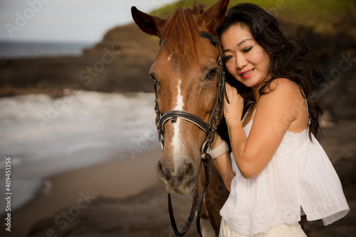 Portrait of Asian woman and brown horse. Woman hugging horse. Romantic concept. Love to animals. Nature concept. Bali