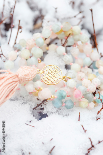 Brass metal spiritual symbol of yantra faceted morganite mala necklace on the white snow photo