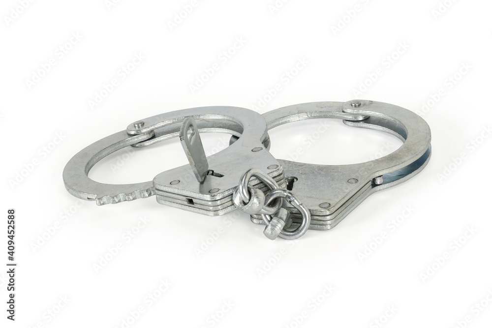 Handcuffs with key isolated on white background with light shadows. Pair of closed silver handcuffs macro close-up high resolution. Handcuffs with key isolated on white background with light shadows. Pair of closed silver handcuffs macro close-up high resolution.