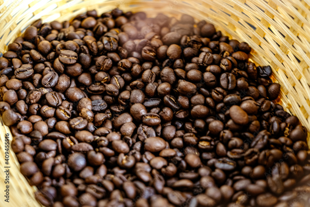 Fototapeta premium Coffee bean in the bamboo basket with a little bit smoke after roasting process. Photo with some part blurred.