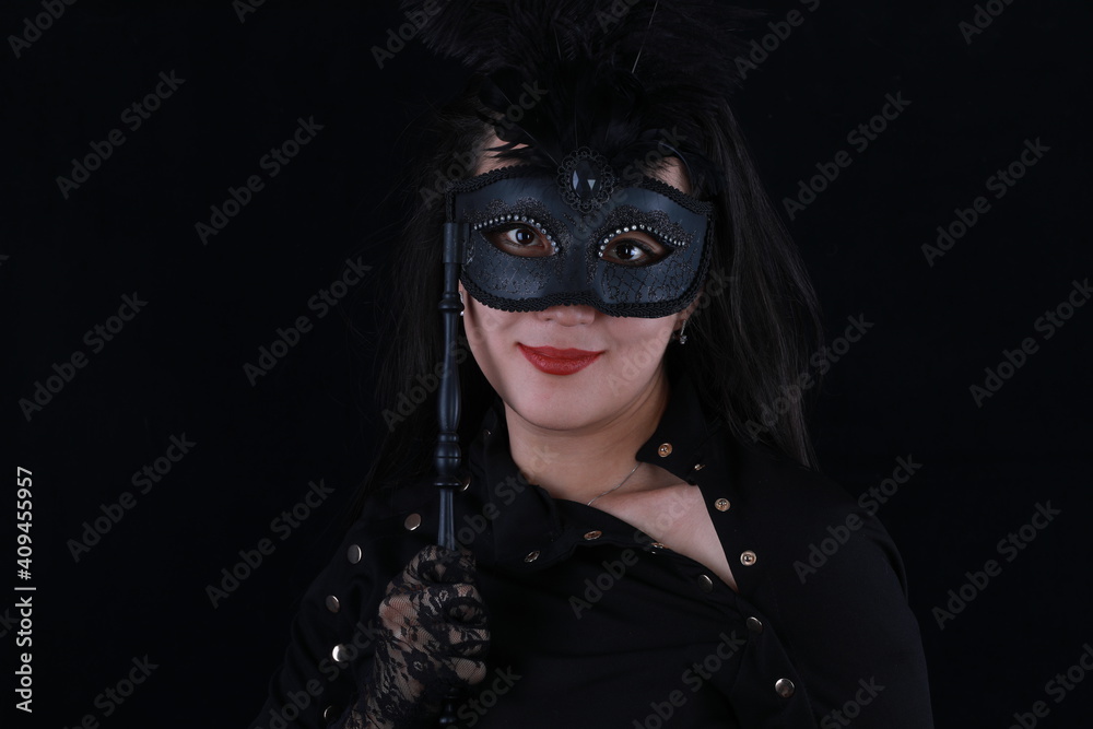 studio portrait of a beautiful girl with a theatrical mask on a black background
