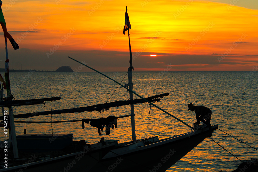 Fisherman and traditional fishing boat under sunset on July 26, 2015 in Java, Indonesia