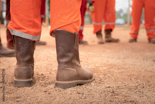 Group safety meeting or toolbox talk with working team action concept photo. Close-up and selective focus at heel part of the leader with blurred background of other working staffs. 