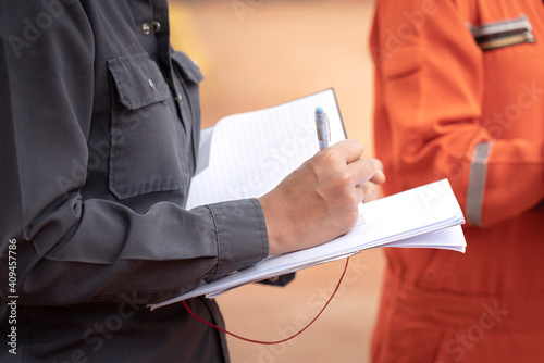Fotografie Safety officer or Supervisor is writing note on the checklist paper during perform audit and inspection in oil field operation