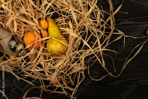 Sweet mandarines with quail eggs and pear on a wooden background. Top view.