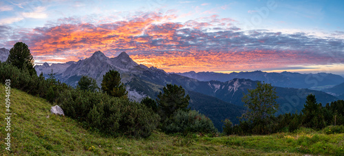 Panorama of Orange clouds after sunset in the alps looks like the sky is on fire with view on mountains Alpsitze and Hochblassen