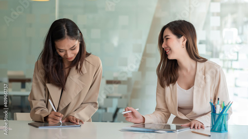 Two beautiful young asian businesswoman working together using digital tablet at office.