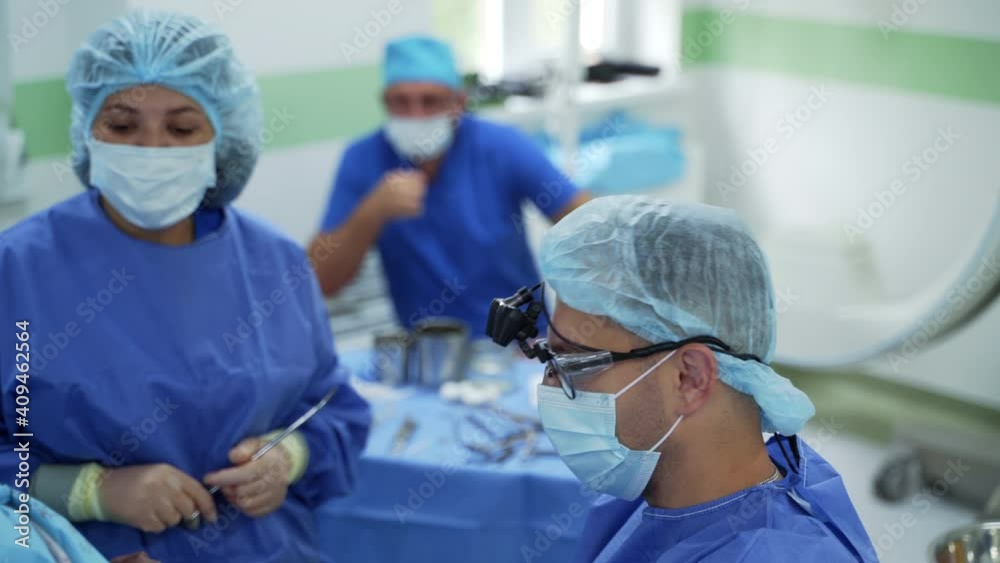 Surgery in the operating theater. Nurse assists surgeon in the operating room. Team of medical workers in protective uniform perform an operation. Surgery in the operating theater. Nurse assists surgeon in the operating room. Team of medical workers in protective uniform perform an operation.