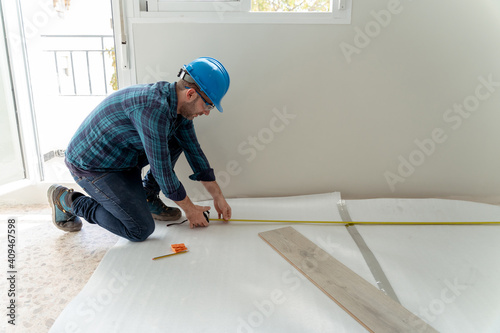 Carpenter worker installing laminate flooring in the room.