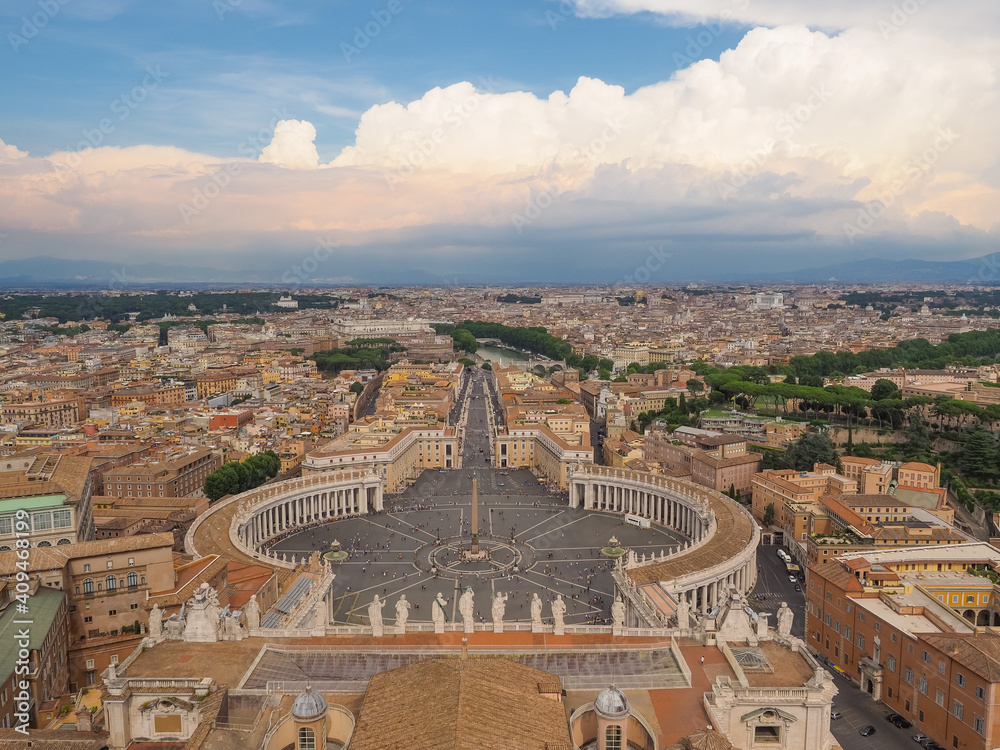 Famous St. Peters Square of Vatican city in the foreground, Via della Conciliazione and cityscape of Rome in the middleground, and blue sky with stormy clouds in the background. View from above. Italy