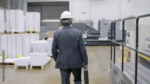 Wallpaper Mural Old male factory engineer wearing formal suit and hardhat, holding toolkit box, walking through plant floor. Dolly shot. Industry and production concept Torontodigital.ca