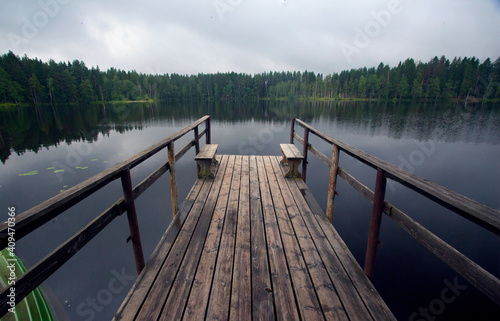 Wallpaper Mural A wooden bridge on a lake in the forest, green fir trees and a cloudy sky. Tourist holidays on the Karelian Isthmus. Torontodigital.ca