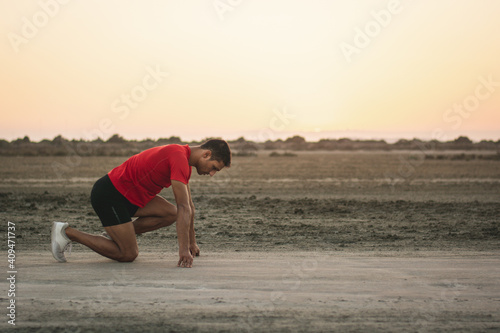 Runner in start position ready to sprint during outdoors training © uplightpictures