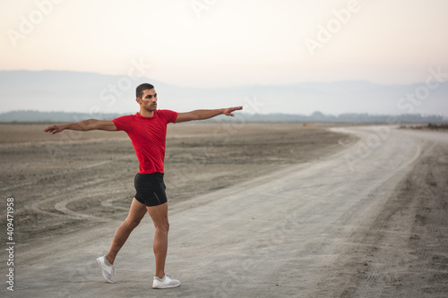 Fit man stretching while training outdoors in nature after sunset