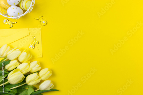 Canvas Print Beautiful yellow tulips with colorful easter eggs, bunnies and envelope on yellow background