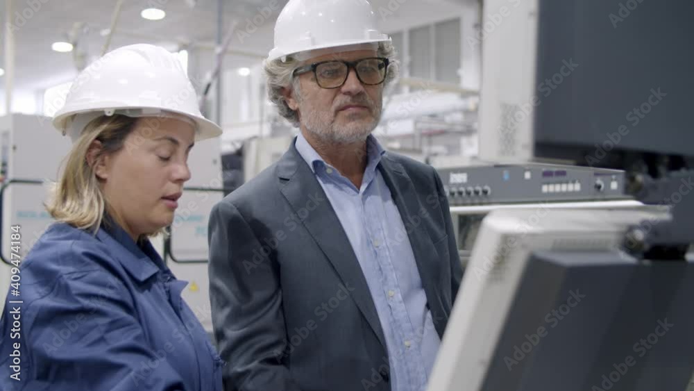 Female factory engineer showing new machines control panel to senior factory owner or investor. Production process or machinery concept Female factory engineer showing new machines control panel to senior factory owner or investor. Production process or machinery concept