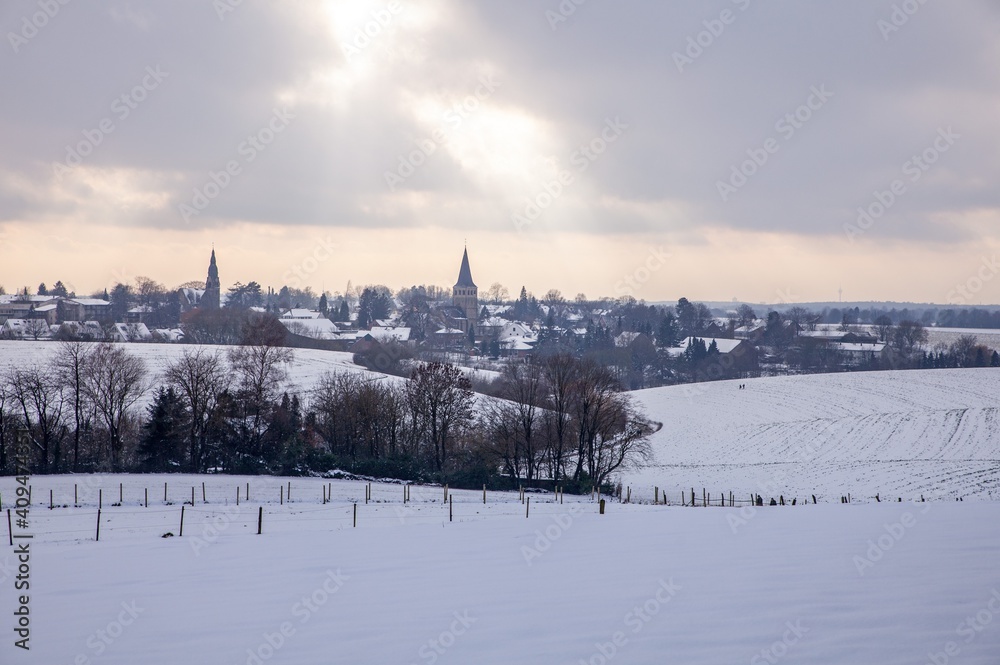 the catholic and protestant church of homberg in winter with snow and clouds and sunlight