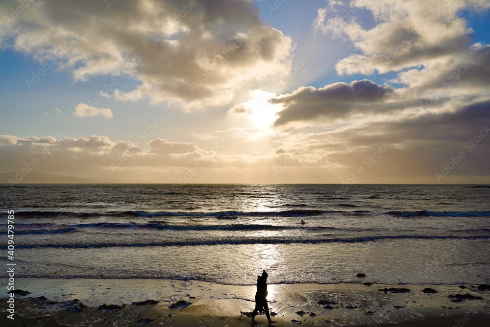 Fototapeta premium girl walking on the beach at sunset silhoette