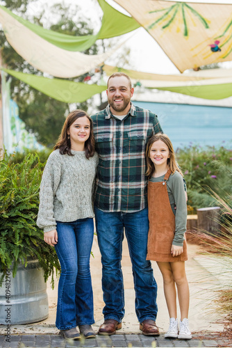 Obraz na plátně A stepfather with his two step daughters standing outside in a downtown park are
