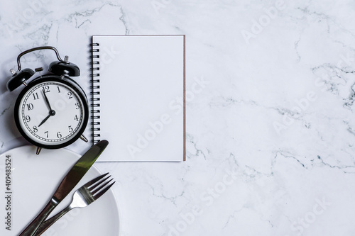 Food clock with notebook. Healthy food concept on white background