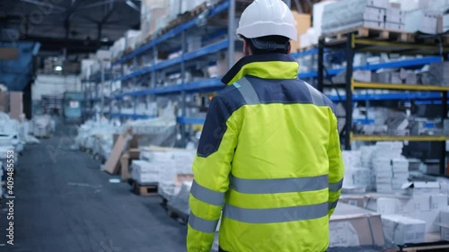 Follow footage of employees male warehouse worker engineer in hard hat working. walking through logistics center warehouse factory construction site logistics architect businessman man builder indoors