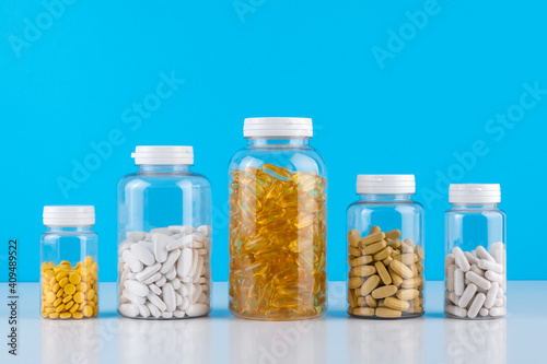 Bottles transparent pills orange capsules blue background. Gel capsules bottle white surface. Nutritional Supplements, Vitamins. Omega 3, multivitamins, Calcium, antibiotics. Health. Immunity