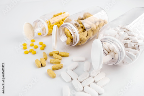 Orange pills, white capsules open transparent bottles with white background. Nutritional supplements, vitamins. Omega 3, multivitamins, Calcium, antibiotics. Medication, pills. Health. Immunity