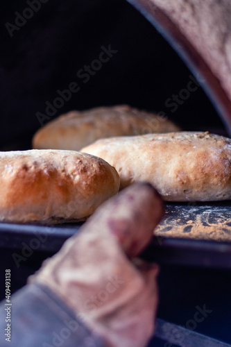 Hot homemade bread with moisture vapor freshly made in a Chilean clay oven with white flour and women's hands Cordoba Argentina