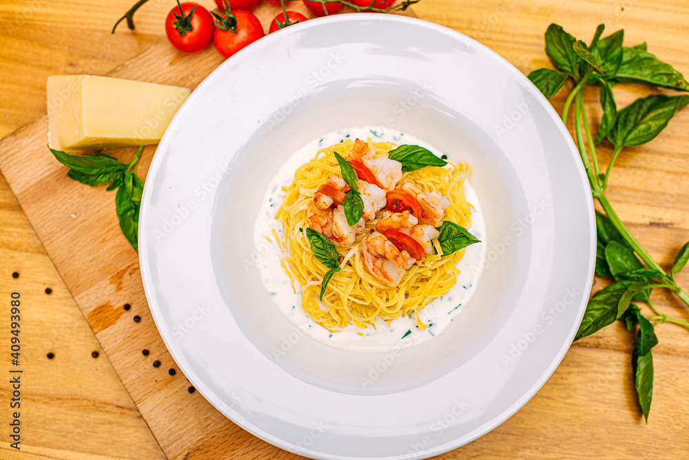 spaghetti with shrimps and tomatoes on a decorated table spaghetti with shrimps and tomatoes on a decorated table