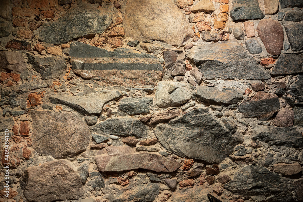 Fototapeta premium Old stone wall. Rough surface of masonry. Granite rock. Stylish interior in a medieval style. Vintage texture great for background and design.
