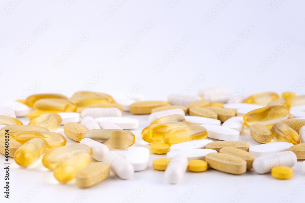 Yellow tablets white capsules gel shell lying on white background close-up. Omega 3, Multivitamins, Calcium, Antibiotics. Health. Immunity. Taking medication, pills. Nutritional supplement. Copy space Yellow tablets white capsules gel shell lying on white background close-up. Omega 3, Multivitamins, Calcium, Antibiotics. Health. Immunity. Taking medication, pills. Nutritional supplement. Copy space