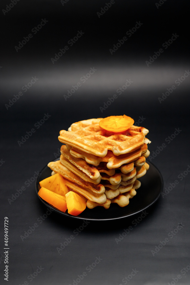 Luxurious traditional waffle pile with ripe raspberries, blueberries and syrup dropping isolated on black background. Culinary sweet dessert. Luxurious traditional waffle pile with ripe raspberries, blueberries and syrup dropping isolated on black background. Culinary sweet dessert.