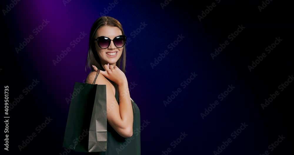 Young caucasian girl 20s years old in casual black dress and sunglasses hold shopping bag with purchases after shopping isolated on black background studio People lifestyle concept Young caucasian girl 20s years old in casual black dress and sunglasses hold shopping bag with purchases after shopping isolated on black background studio People lifestyle concept