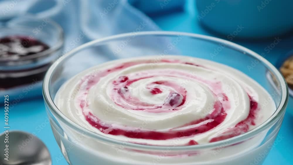 Yogurt with berry jam in spoon, curd cream swirl with fruit topping, blueberry whipped cream, ProRes uncompressed video