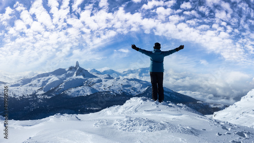 Adventurous Girl on top of a beautiful snowy mountain during a vibrant and sunny winter day. Hands Up. Blue Sky Art Render. Taken in Whistler, British Columbia, Canada.