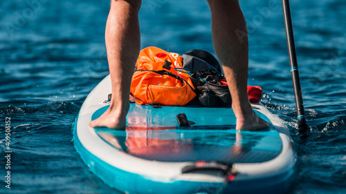 Valokuva Young athletic man paddling on a SUP stand up paddle board in blue water sea in
