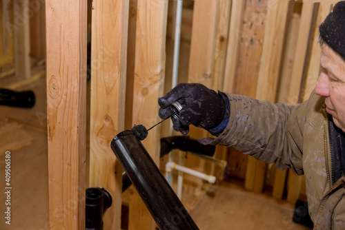 Plumber joining PVC sewage drain pipes on a home under construction